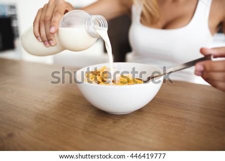 Beautiful young woman's hands holding bottle and pour milk in bowl