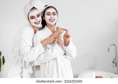 Beautiful young women with applied facial masks in bathroom - Powered by Shutterstock