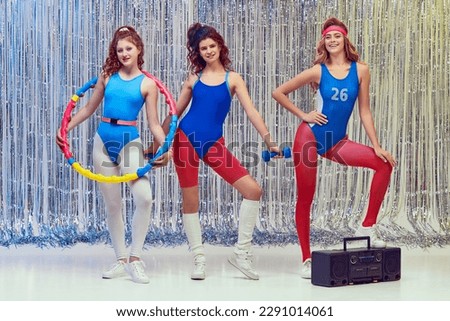 Beautiful young women in blue and red sportswear training fit fitness equipments, doing stretching and aerobics exercises. Concept of retro fitness, sport, 80s fashion, beauty, health