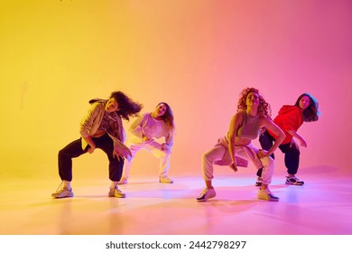 Beautiful young women, dancers in motion in casual clothes dancing against gradient background in neon light. Concept of youth, street dance, contemporary dance, modern, dynamics - Powered by Shutterstock