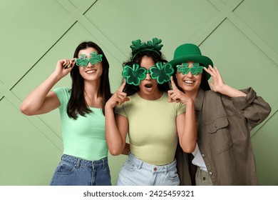 Beautiful young women in decorative glasses in shape of clover on green background. St. Patrick's Day celebration - Powered by Shutterstock