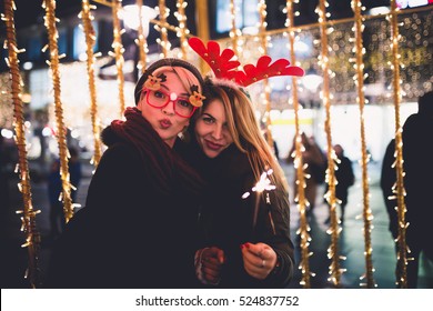 Beautiful young women enjoying Christmas or New Year night on a city street. 