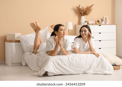 Beautiful young women with lip mask and under-eye patches lying on bed at home - Powered by Shutterstock