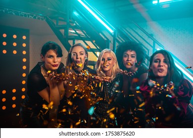 Beautiful young women partying in a nightclub and blowing confetti - Shutterstock ID 1753875620