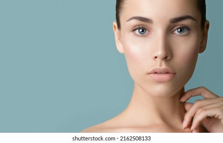 Beautiful young women with perfect fresh skin and makeup touches her face. Portrait of model with make-up, eyebrows  and long eyelashes. Beauty and Spa, skincare and wellness. Selective focus