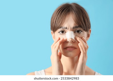 Beautiful young worried woman with bandaged nose on blue background. Plastic surgery concept - Powered by Shutterstock