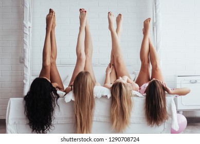 Beautiful Youth. Four Young Women With Good Body Shape Lying On The Bed With Their Legs Up.