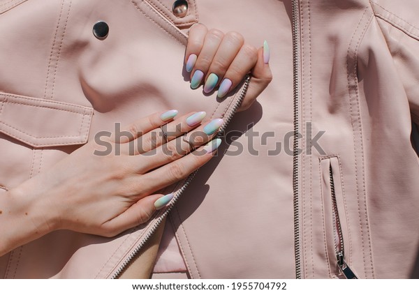 Beautiful youth manicure. The design is a mix of pink\
and blue. Unicorn color varnish. Gel polish nail polish. Spring\
fresh trend summer. Flatlay. Phalanx ring. Leather jacket young\
look close up