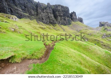 Beautiful,dramatic Scottish mountainous scenery,pointed,jagged mountain peaks and sheer cliff faces, along the Quiraing hills walk,green grass and shrub covered in the mid summer,north eastern Skye.