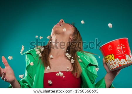 Beautifull girl is trying to catch the popcorn that she thrown with her mouth
