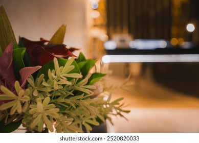 A beautifully arranged bouquet of red and pink flowers with green foliage, set against a blurred background of a modern, elegant luxury hotel interior. - Powered by Shutterstock