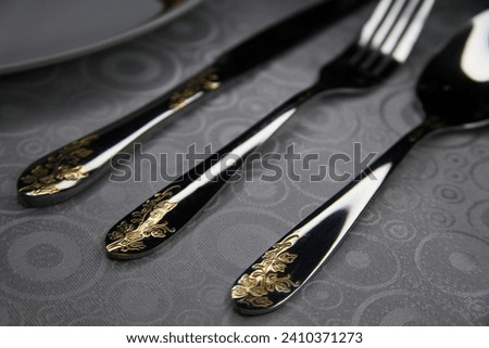beautifully arranged cutlery in shiny stainless steel with patterns on the handles of spoons, forks and knives. contrast photo of table setting. close-up photo of cutlery on a white tablecloth. 