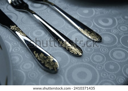 beautifully arranged cutlery in shiny stainless steel with patterns on the handles of spoons, forks and knives. contrast photo of table setting. close-up photo of cutlery on a white tablecloth. 