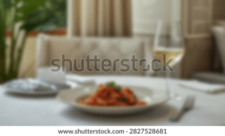 A beautifully arranged dining table features a plate of pasta, a glass of white wine, and soft ambient lighting.