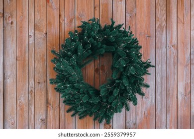 Beautifully crafted Christmas wreath made of pine branches and decorative elements on brown wooden wall illuminated by soft, warm fairy lights background. Festive home decor, winter holiday atmosphere - Powered by Shutterstock