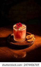 A beautifully crafted cocktail with a vibrant flower garnish, served in a stylish glass on a wooden tray.