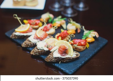 Beautifully Decorated Catering Banquet Table With Different Food Snacks And Appetizers With Sandwich, Caviar, Fresh Fruits On Corporate Christmas Birthday Party Event Or Wedding Celebration