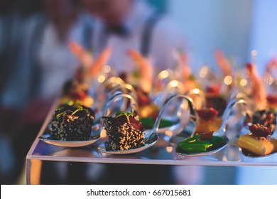 Beautifully decorated catering banquet table with different food snacks and appetizers with sandwich, caviar, fresh fruits on corporate party event or wedding celebration
