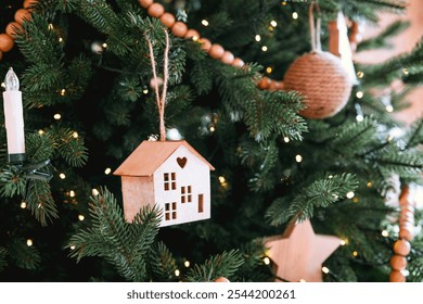 A beautifully decorated Christmas tree adorned with lights, wooden ornaments, and a house-shaped decoration adds warmth and cheer to the holiday season in a cozy home setting. - Powered by Shutterstock