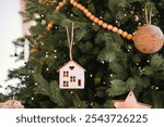 A beautifully decorated Christmas tree features wooden house ornaments and soft lights. The scene captures a cozy holiday atmosphere, perfect for family gatherings and celebrations.