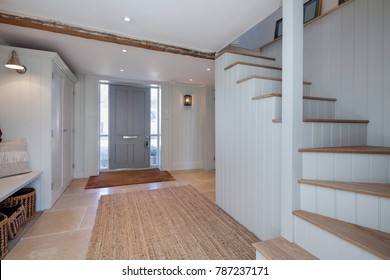 Die elegante Eingangshalle mit hellblauen Wänden, Sitzbank, Tür, großen Teppichen und Treppen ist in einem modernen Stil eingerichtet – Stockfoto
