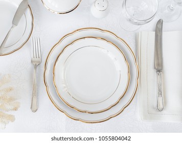 Beautifully decorated table with white plates, glasses, antique cutlery and white coral on luxurious tablecloths