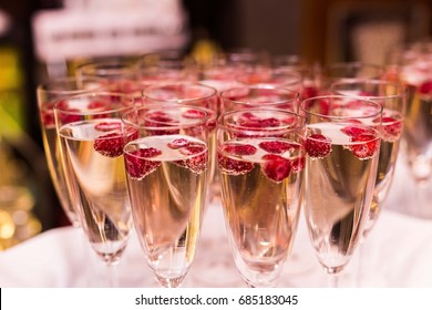 Beautifully decorated welcome drink - a glass of Prosecco or champagne with raspberry inside, served as a welcome drink on a party, event, wedding reception or banquet.