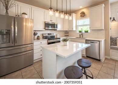Beautifully designed kitchen with center bar, tile floor, French door fridge, stove and microwave, dishwasher, deep sink and faucet.