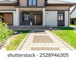 A beautifully designed modern house, featuring brick details, a landscaped yard, and a welcoming entrance pathway.