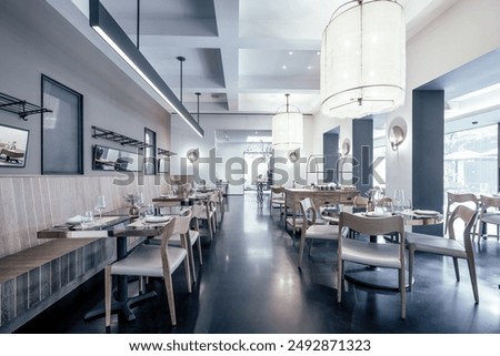 A beautifully designed restaurant interior showcasing a modern and elegant dining area. The space features contemporary furniture, including wooden chairs and tables set with glassware, plates.