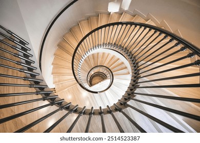 A beautifully designed spiral staircase with wooden steps and black metal railings, creating a mesmerizing symmetrical pattern viewed from above. - Powered by Shutterstock