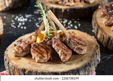 Beautifully Grilled Lamb Rib Chop Steaks, Medium Rare With Fried Potato Chips On Wood Serving Board.