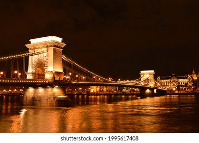 A beautifully illuminated chain bridge at night. The Széchenyi Chain Bridge spans the river Danube between Buda and Pest, the western and eastern sides of Budapest, the capital of Hungary.