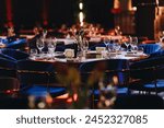 Beautifully organized event - round served table banquet ready for guests, round decorated table with empty plate, glasses, forks, napkin. Elegant dinner table 