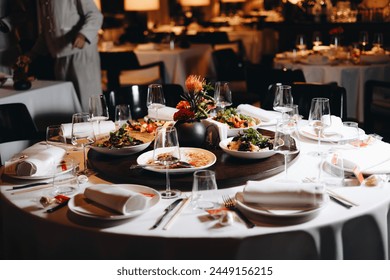 Beautifully organized event - round served table banquet ready for guests, round decorated table with empty plate, glasses, forks, napkin. Elegant dinner table  - Powered by Shutterstock