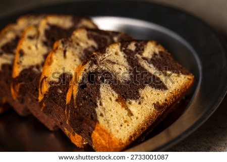 The beautifully patterned marble pound cake, once sliced, presents an enticing texture under natural light.