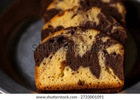 The beautifully patterned marble pound cake, once sliced, presents an enticing texture under natural light.
