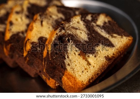 The beautifully patterned marble pound cake, once sliced, presents an enticing texture under natural light.