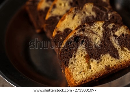 The beautifully patterned marble pound cake, once sliced, presents an enticing texture under natural light.