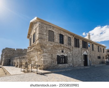 A beautifully preserved historic stone building in Larnaca showcasing traditional architecture, with arched windows, a wooden door, and cultural significance. - Powered by Shutterstock