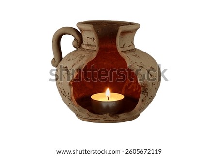 A beautifully rustic ceramic lantern with an open, broken-jug design, housing a softly glowing candle. 