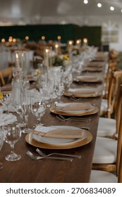 A beautifully set dinner table with elegant tableware, candles, and floral decorations, perfect for a wedding or formal event.