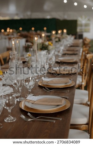 A beautifully set dinner table with elegant tableware, candles, and floral decorations, perfect for a wedding or formal event.