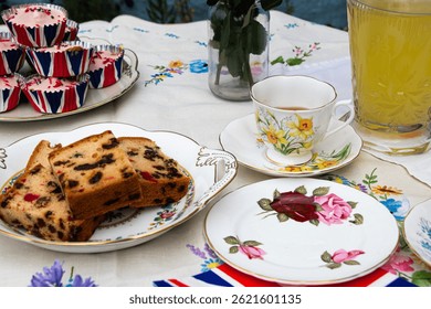 A beautifully staged VE Day 80th Anniversary celebration capturing the essence of British heritage and royal tradition. Set in a picturesque garden or village green, the vintage afternoon tea party 