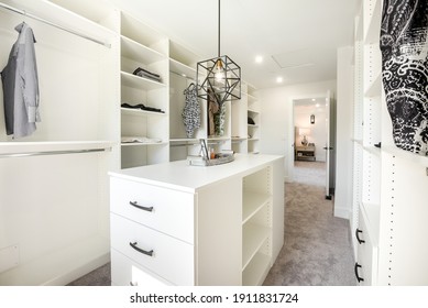 beautifully staged walk in closet with custom white cabinets