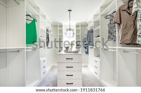 beautifully staged walk in closet with custom white cabinets