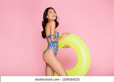 Beautiful,Sexy asian girl standing on pink background in a colors bathing suit bikini and smiling.perfect for photo advertisements, style vogue