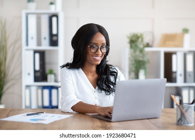 Beautuful black businesswoman working with laptop computer at desk in office. African American female entrepreneur typing document, checking email, participating in online meeting at workplace - Shutterstock ID 1923680471