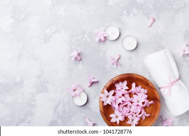 Beauty, Aromatherapy And Spa Background With Perfumed Pink Flowers Water In Wooden Bowl And Candles On Stone Table. Top View, Flat Lay.