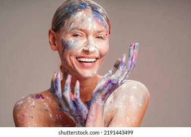 Beauty Art Portrait Of A Smiling Female Painter With Colorful Paints On Hands And Face. Happy Woman. Real Emotions.